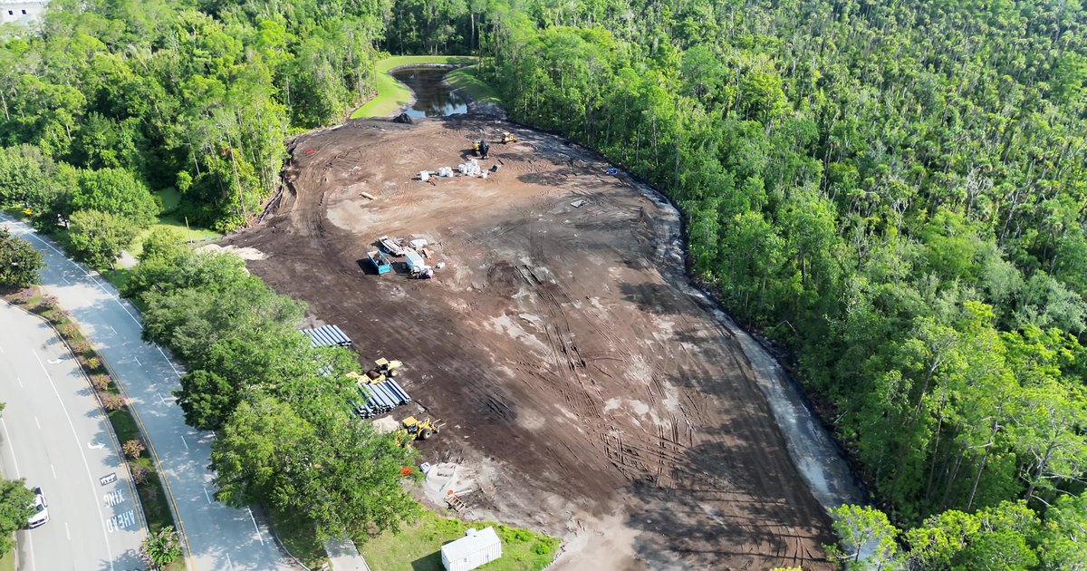 Aerial view of an active Northeast Florida earthwork site, cleared pad bounded by tree line and an adjacent roadway.